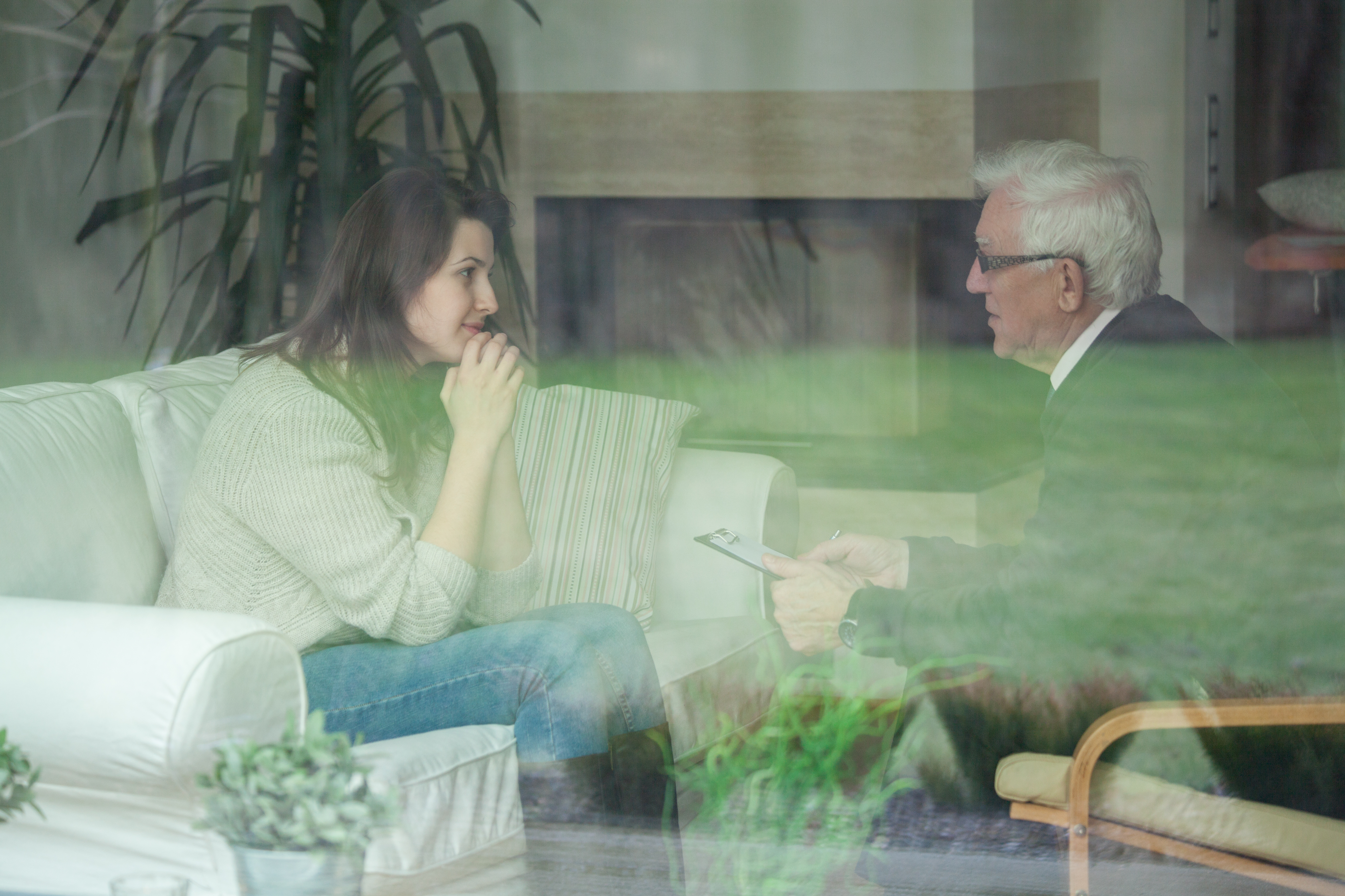 Elder therapist consulting young patient at home